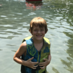 Child standing in water smiling supported by Give Hope Nevada